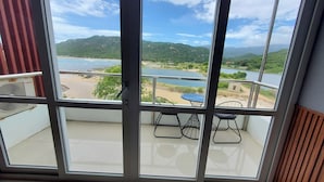 Een balkon met uitzicht op een strand en bergen.