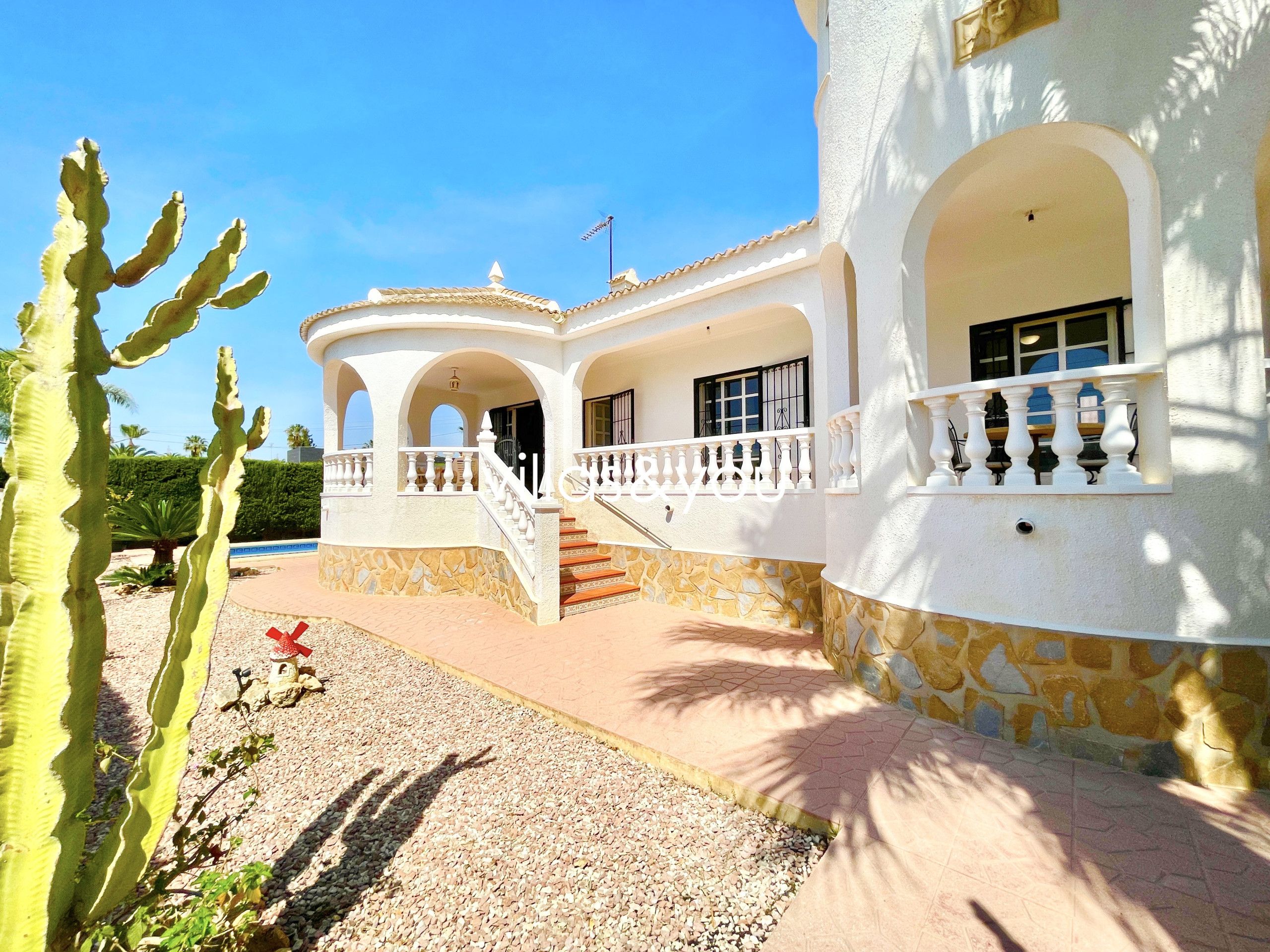 A building with a white exterior, stone accents, and a central staircase leading to a balcony.