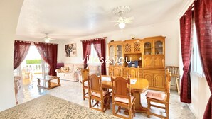 Ein geräumiges Wohnzimmer mit Essbereich, Holzmöbeln und Deckenventilator.
