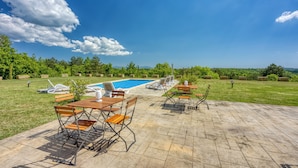 A poolside area with lounge chairs, a wooden table, and a view of the pool and surrounding greenery. - Grad Inn Room Thyme With Pool (Koper)
