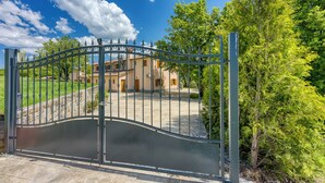 A gated entrance to a property with a paved driveway leading to a building with a tiled roof. - Grad Inn Room Thyme With Pool (Koper)