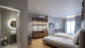 A modern hotel room with a wooden floor, a sofa bed, a built-in wardrobe, a mirror, and a TV. - Hotel Kroi (Ksamil)