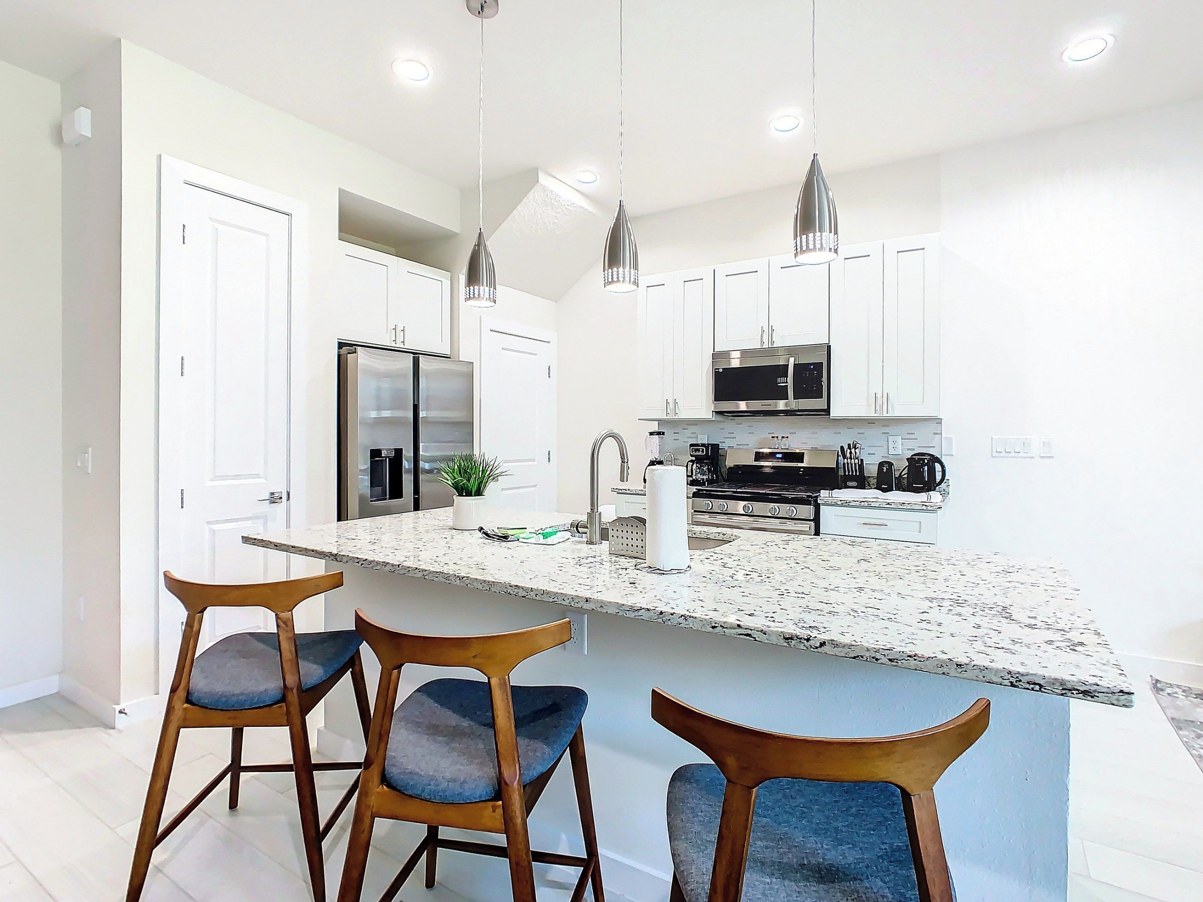 A modern kitchen with a central island, stainless steel appliances, and pendant lighting.