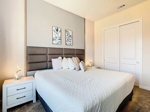 A bedroom with a bed, bedside tables, a wardrobe, and two wall-mounted artworks.