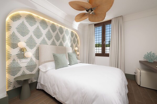 A bedroom with a bed, a ceiling fan, a window with curtains, and a wall with leaf-pattern wallpaper. - Casa Postigos (Marbella)