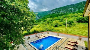 A swimming pool with a view of green hills and a cloudy sky. - Stars Residence (Petrovac)