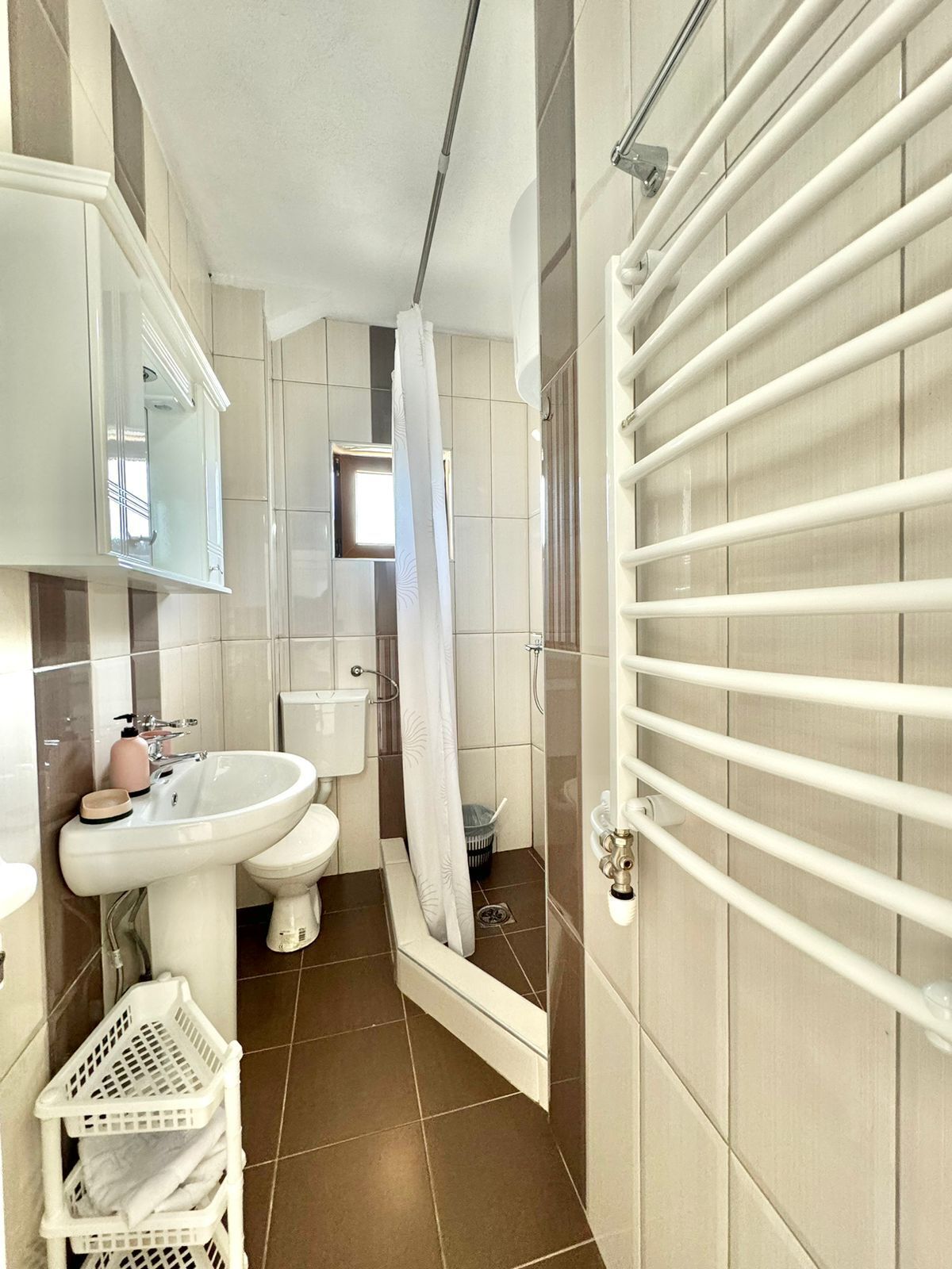 A compact bathroom with a sink, toilet, and shower.