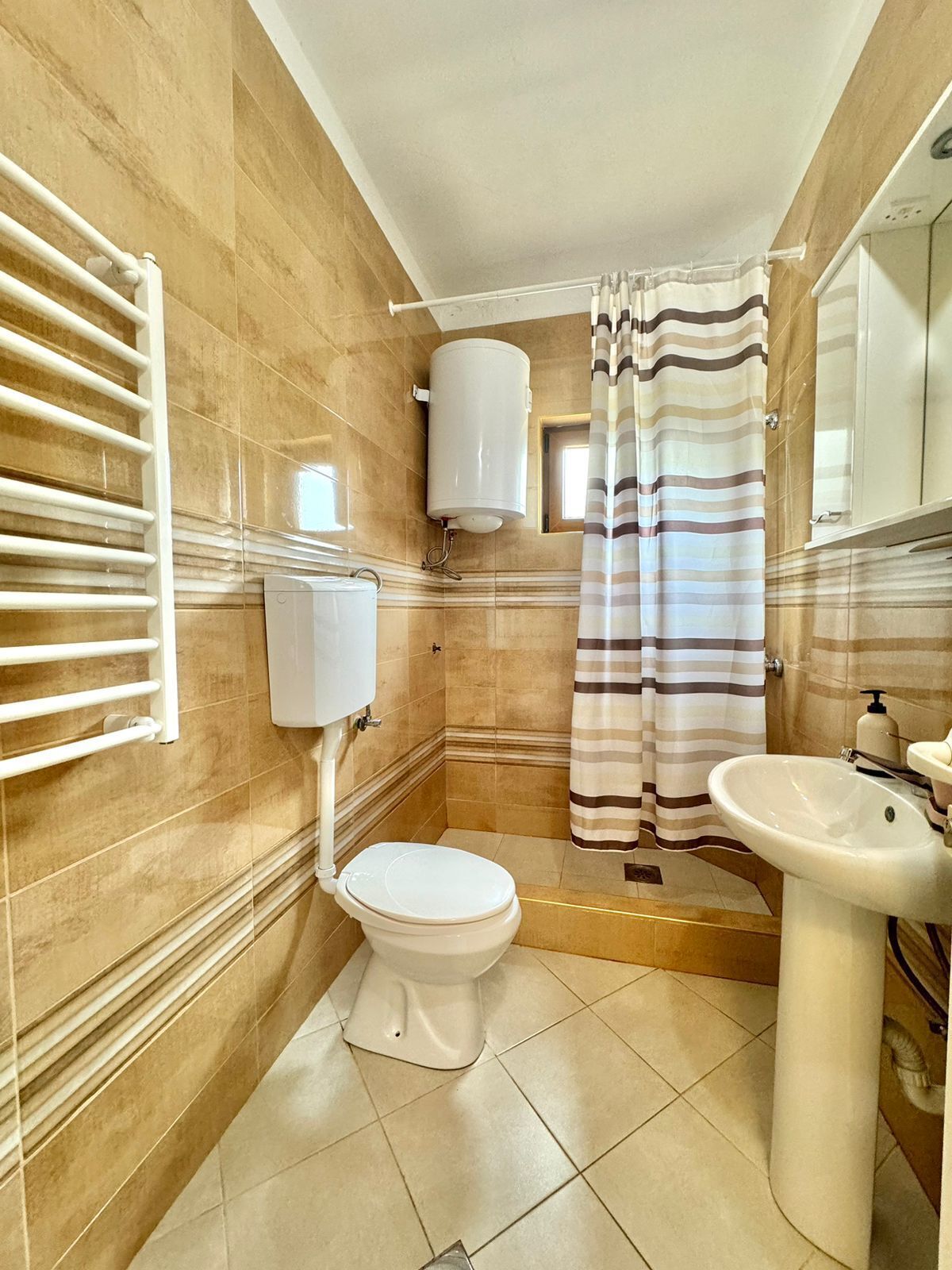 A bathroom with a toilet, a sink, a shower curtain, and a towel rack.