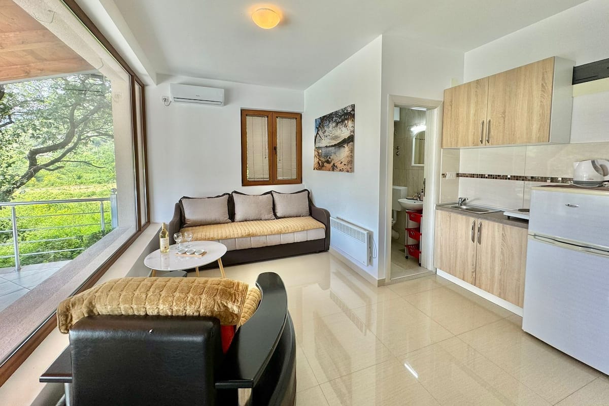 A modern living room with a sofa, a dining table, and a kitchen area with cabinets and appliances.