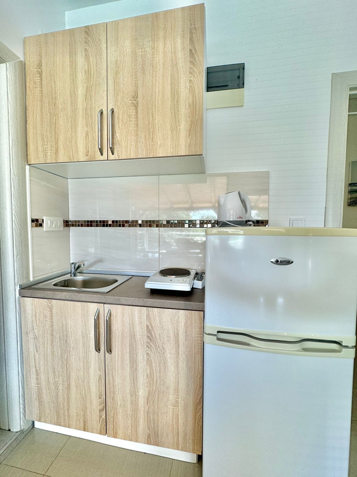 Una cucina con mobili in legno, un frigorifero bianco, un lavello e una macchina da caffè.