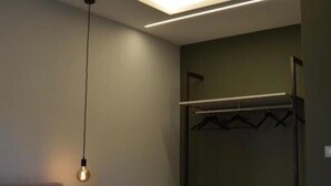 Een moderne kamer met een hanglamp, een kapstok en een zichtbare kastdeur.