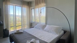 Een hotelkamer met een bed, een bureau, een stoel en een groot raam met gordijnen.