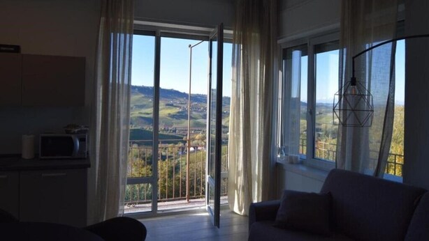 Een kamer met een grote schuifdeur die uitkomt op een balkon met uitzicht op het platteland.