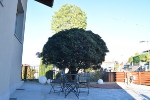 Un espace extérieur aménagé avec une table et des chaises, un grand arbre et une clôture.