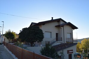 Un bâtiment à deux étages doté d’un balcon, d’un escalier et d’un arbre devant.