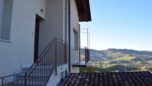 Un bâtiment doté d’un balcon donnant sur un paysage vallonné.