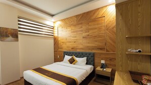 A neatly made bed with a headboard, a bedside table with a phone, and a wooden wall paneling. - LuckyStar Hotel (Pleiku)
