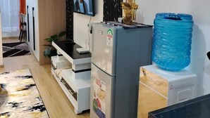 A modern kitchen with a refrigerator, a water dispenser, and a television mounted on the wall.