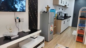 A modern kitchen with a built-in refrigerator, a coffee machine, and a TV mounted on the wall.