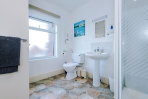 Une salle de bain avec des toilettes, un lavabo et une douche.
