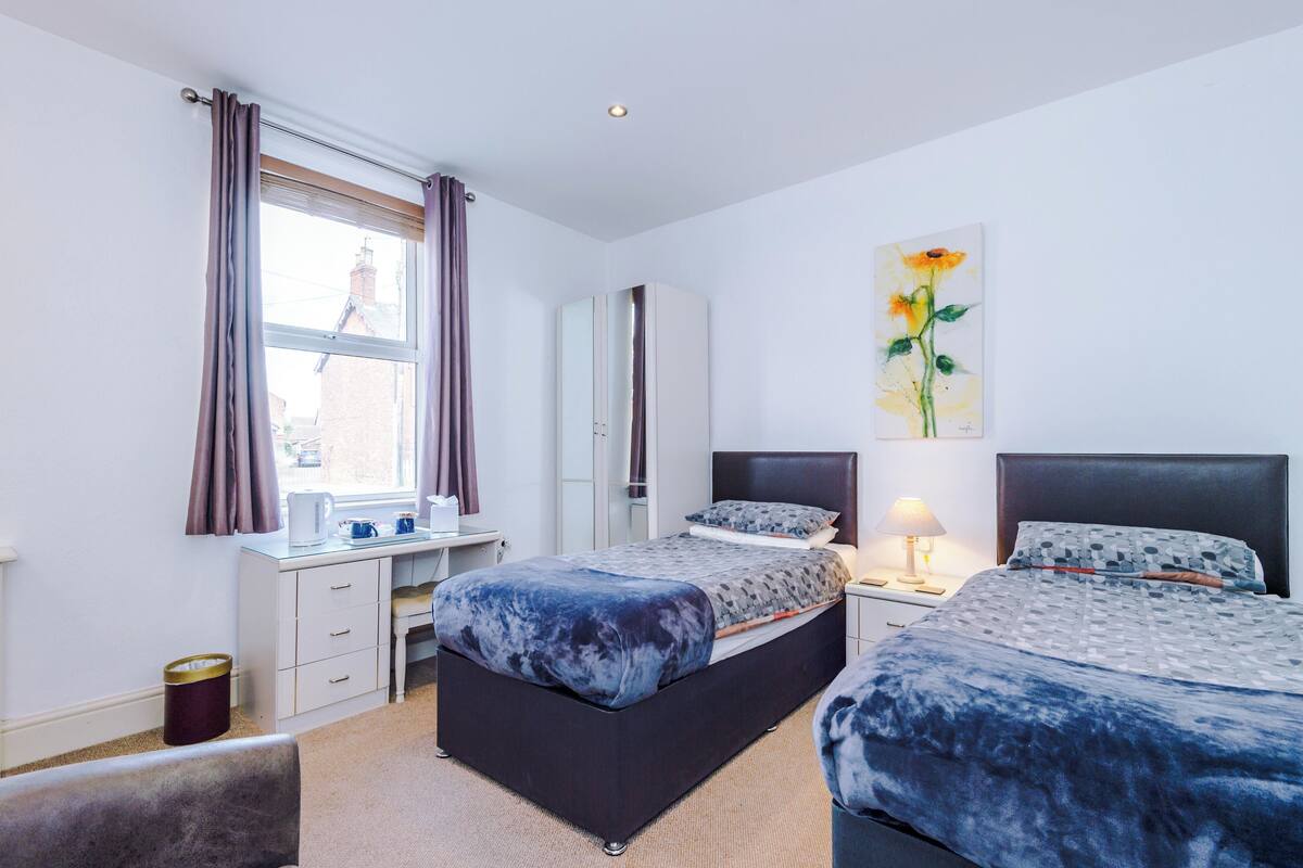 Un dormitorio con cama, escritorio, silla, armario y un cuadro en la pared.