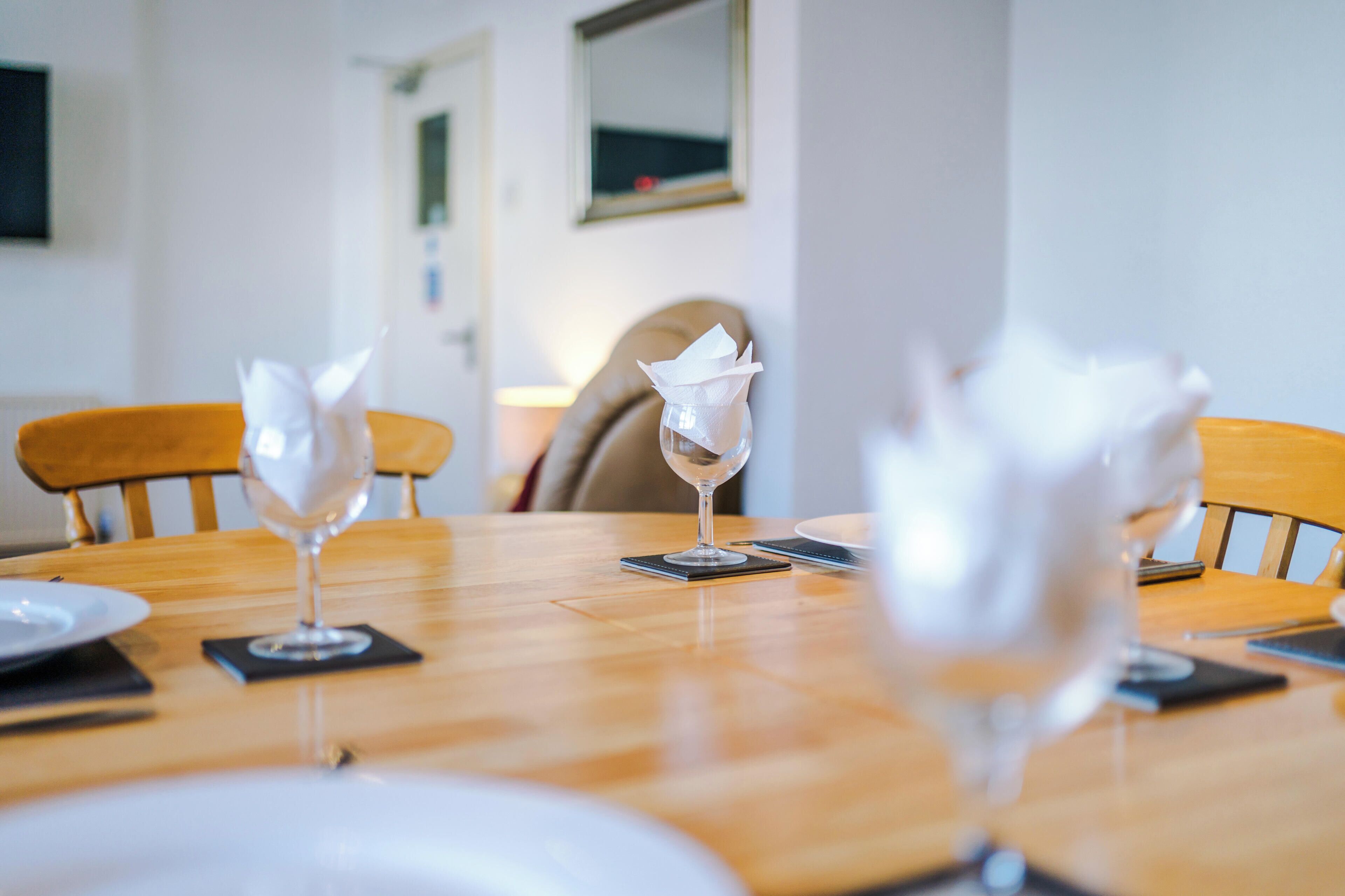 A dining table with four wine glasses and napkins, set for four people.