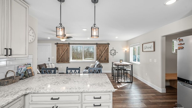 A kitchen with a large island, wooden cabinets, and pendant lighting.