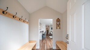 A hallway with wooden benches, a coat rack, and a door leading to a kitchen area.