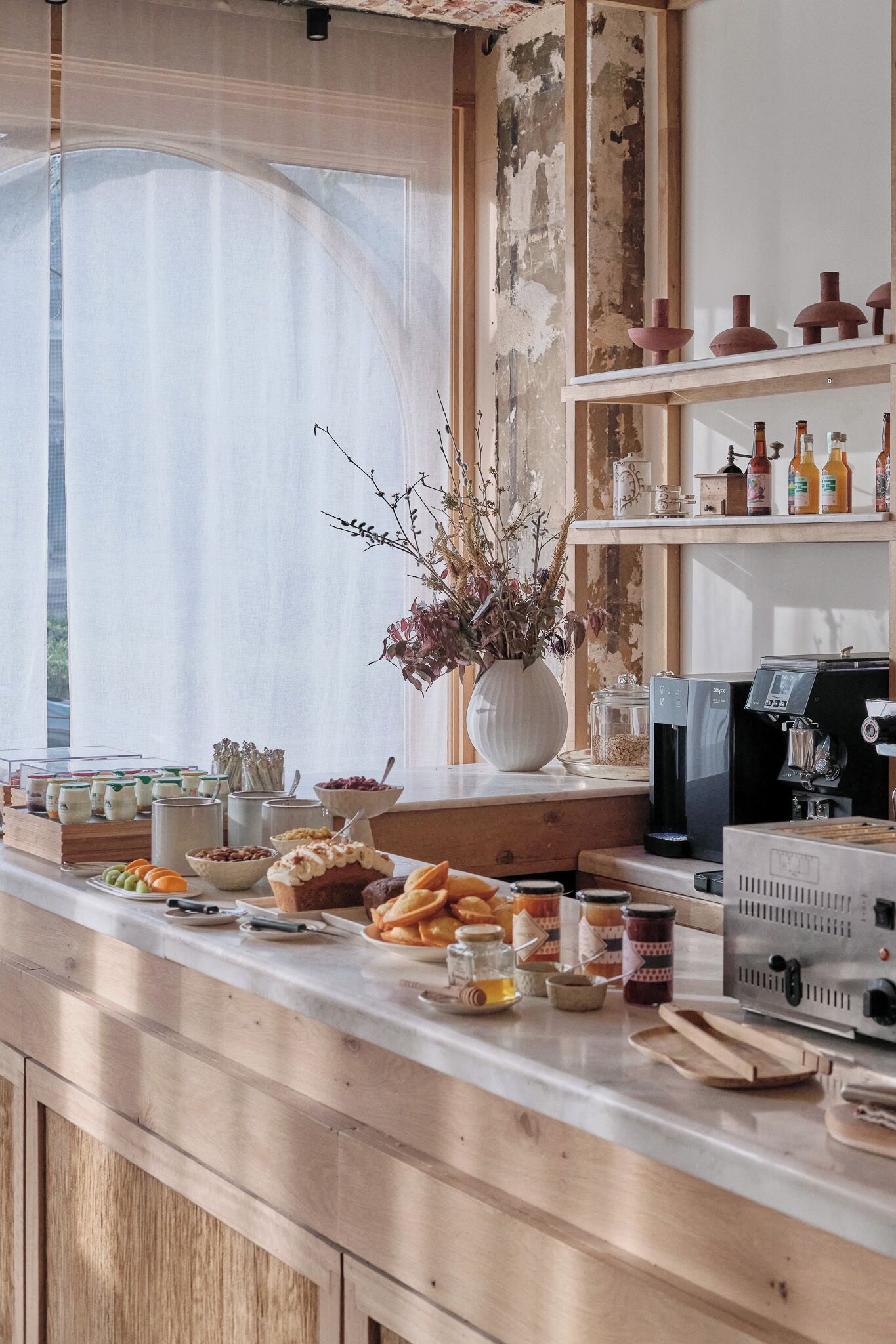 Una encimera de cocina con diversos alimentos, una cafetera y un jarrón con flores secas.