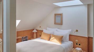 A modern hotel room with a neatly made bed, a bedside table with a lamp, and a framed picture on the wall.