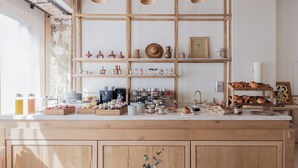 Une cuisine avec des meubles de rangement en bois, un plan de travail sur lequel sont disposés divers aliments et des luminaires suspendus.