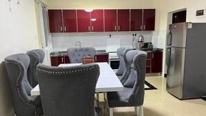 Una cocina compacta con armarios rojos, una encimera blanca y un refrigerador de acero inoxidable.