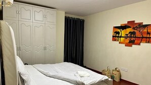 Un dormitorio con cama, armario y un cuadro en la pared.