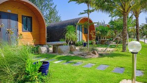 A row of wooden pod-style accommodations with a stone pathway and lush greenery.