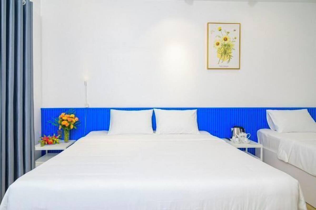 Une chambre d’hôtel avec un grand lit, deux tables de chevet et une illustration botanique encadrée accrochée au mur.