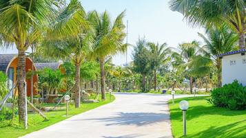 A pathway lined with palm trees and a building with a curved roof.