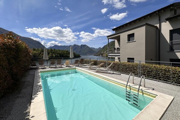 Una piscina con sillas de descanso y vistas a montañas.