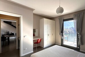 Een slaapkamer met een groot bed, een bureau, een stoel, een kledingkast en uitzicht op zee.
