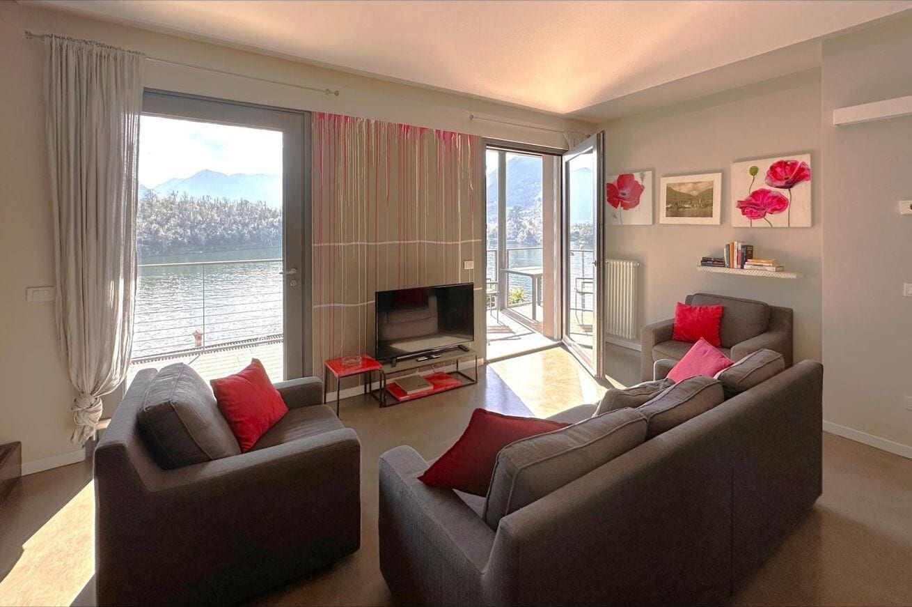 Ein modernes Wohnzimmer mit einer Sofagarnitur, einem Flachbildfernseher und Seeblick.