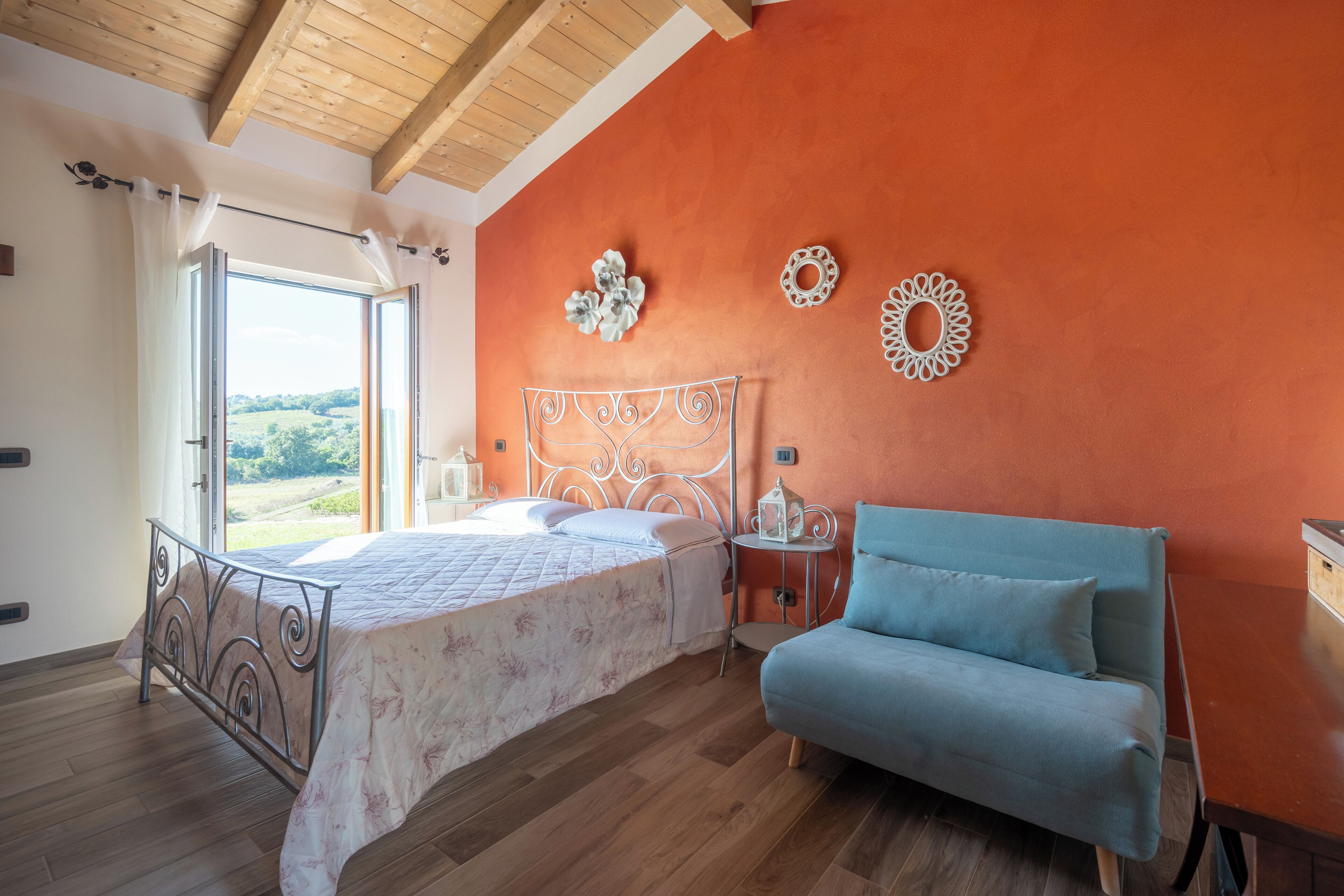 A bedroom with a bed, a blue sofa, and decorative wall art.