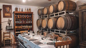 A wine cellar with wooden barrels, a wine rack, and a table set for dining. - Agriturismo Podere Ristella - Wine&Food (Roccastrada)