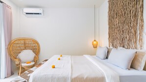 Ein Schlafzimmer mit einem Bett, einem Korbstuhl, einer Bank und einer Wandklimaanlage.