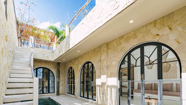 Ein modernes Interieur mit einer Steinwand, einem Pool und Bogenfenstern.