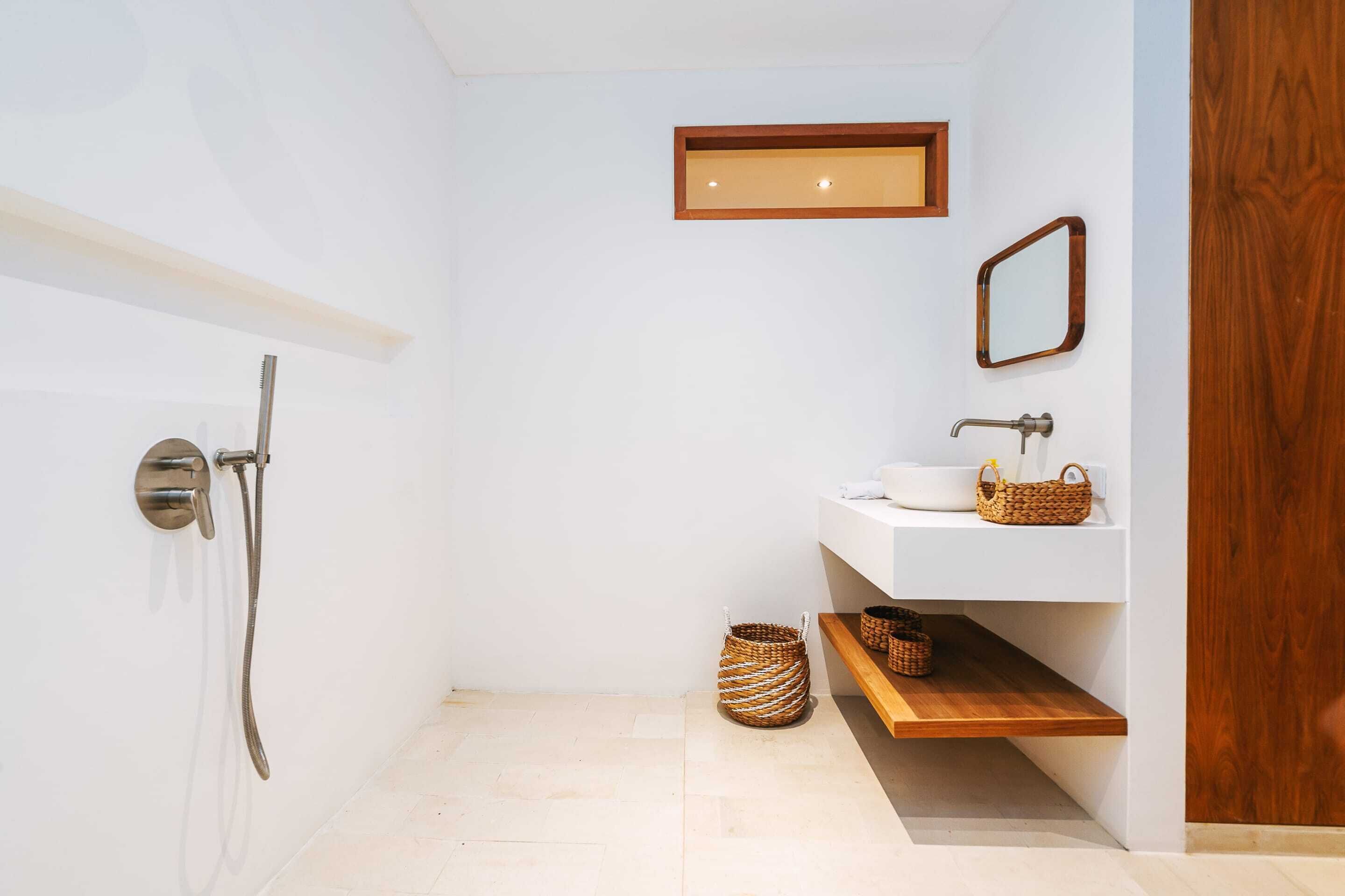 Un baño moderno con ducha, lavabo y estante de madera.
