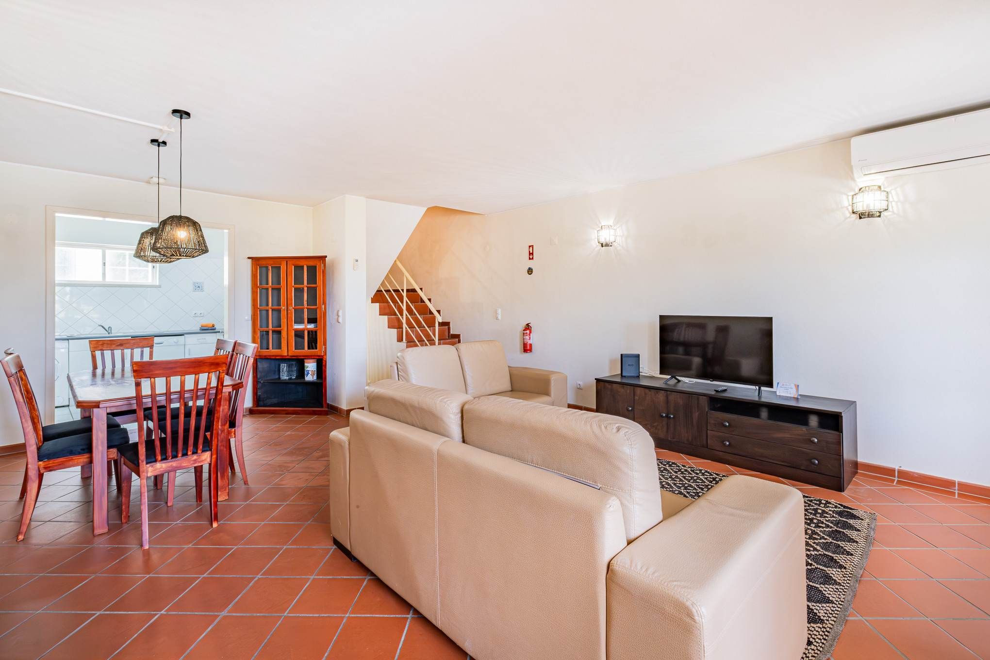 A living room with a sofa, TV, and a dining area with chairs and a table.