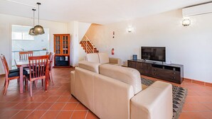 A living room with a sofa, TV, and a dining area with chairs and a table. - Villa Lychee - 350 m from the beach (Guia)