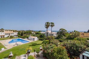 Zona residencial con piscina, palmeras y vista al mar.
