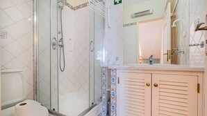 A bathroom with a glass-enclosed shower, a toilet, and a vanity with a mirror. - Villa Lychee - 350 m from the beach (Guia)