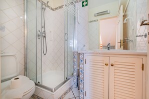 Une salle de bain avec une douche à parois de verre, des toilettes et un meuble-lavabo avec un miroir.