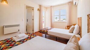 A hotel room with two beds, a window with curtains, a radiator, and a wall-mounted lamp. - Villa Lychee - 350 m from the beach (Guia)